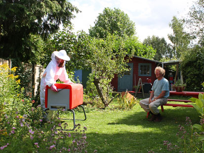 Photo of a Beekeeper working with a Beehaus in his garden