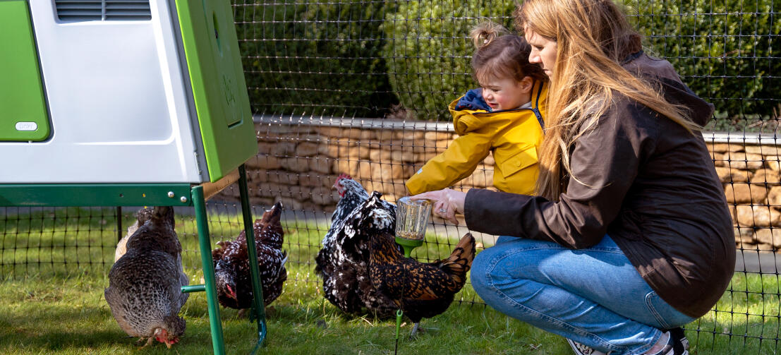 Mutter und Tochter verbringen neben dem Eglu Cube Hühnerstall Zeit mit ihren Hühnern