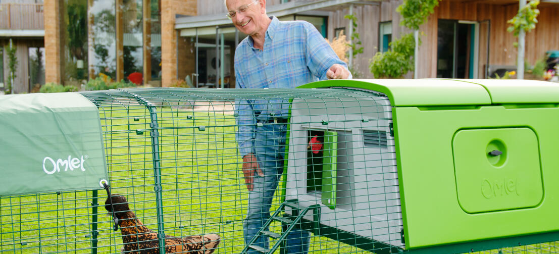 Mann mit großem Eglu hühnerstall und auslauf in einem garten