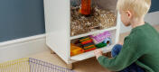 Ein Junge legt Hamsterstreu, Spielzeug und Zubehör in den Stauraum.