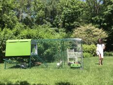 Ein junges mädchen in einem garten mit einem grünen Cube hühnerstall und einem angeschlossenen auslauf