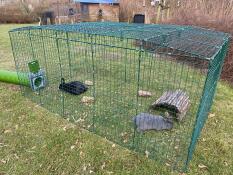 Zwei kaninchen in ihrem gehege, das mit einem grünen tunnel verbunden ist