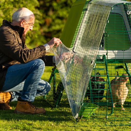 Mann beim anbringen des Eglu Go hühnerstalls mit durchsichtiger auslaufabdeckung