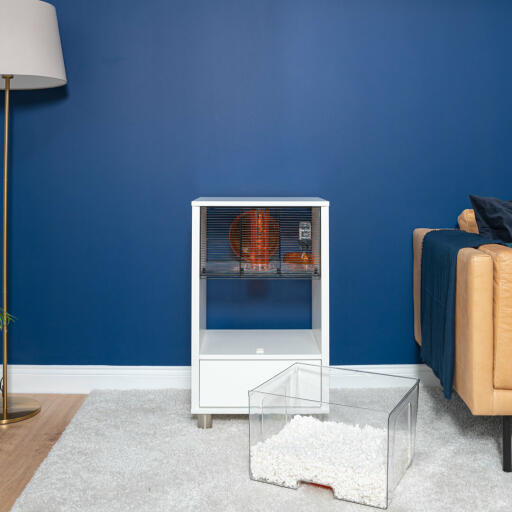 Moderner weißer Qute Hamsterkäfig in einem Wohnzimmer mit herausgenommener Einstreuschublade.