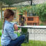 Mädchen beobachtet kaninchen beim fressen von leckereien auf Zippi plattformen von Omlet Caddi leckerbissenhalter im inneren von Zippi kaninchenlaufstall mit Zippi tunnel verbunden