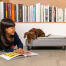 Hund sitzend auf Omlet Topology hundebett mit gestepptem topper und schwarzen schienenfüßen untersucht mädchenbuch