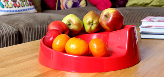 A Red Rollabowl fruit bowl on a coffee table.