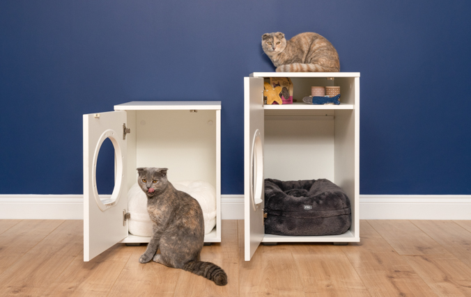 Zwei Katzen und zwei Modelle des modernen Maya Katzenhauses mit geöffneten Türen, die das Ablagefach des Katzenhauses zeigen