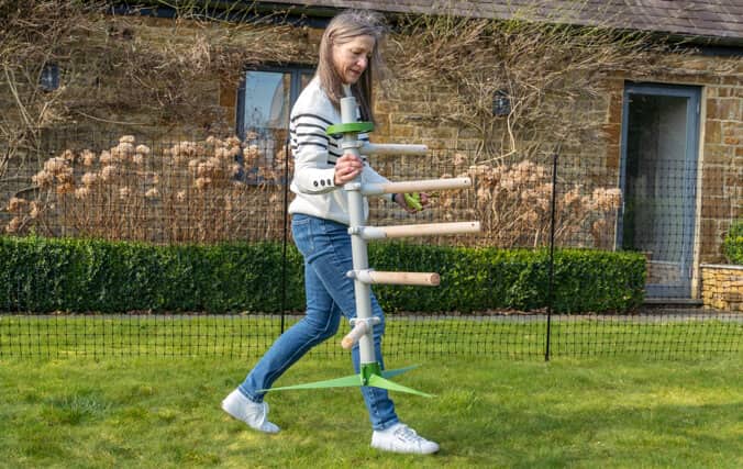 Eine Frau versetzt mühelos das freistehende Hühnerstangensystem